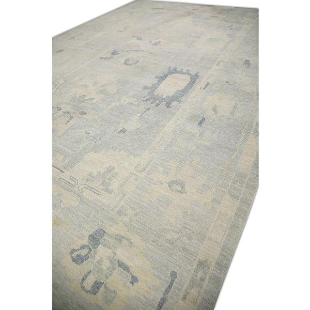 This modern Turkish Oushak rug is a stunning piece of art that has been handwoven using traditional techniques by skilled...