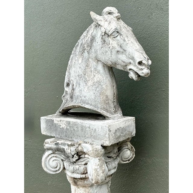 This vintage cast stone horse sculpture is mounted on a tall, spiraled column, creating a striking architectural accent....