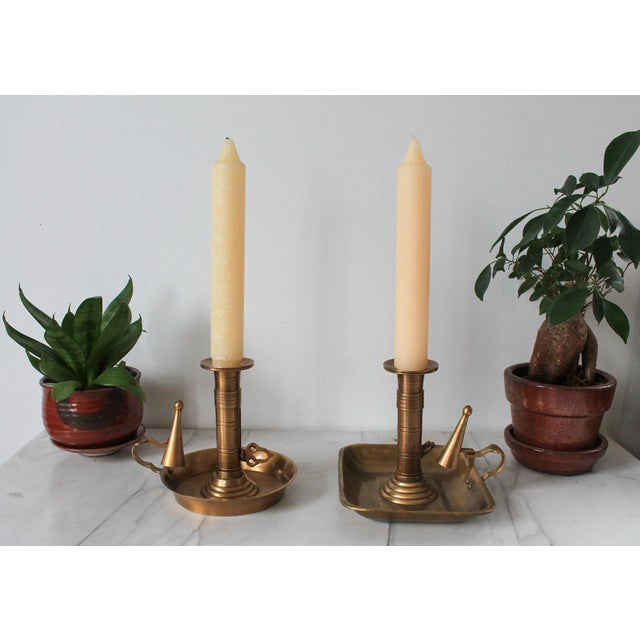 Pair of vintage brass chamberstick candle holders, designed with a finger loop for carrying and an attached snuffer. Each...