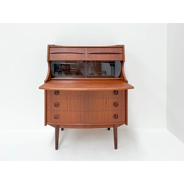 This elegant vintage secretary desk is made of warm teak wood and features a timeless mid-century modern design. It offers...