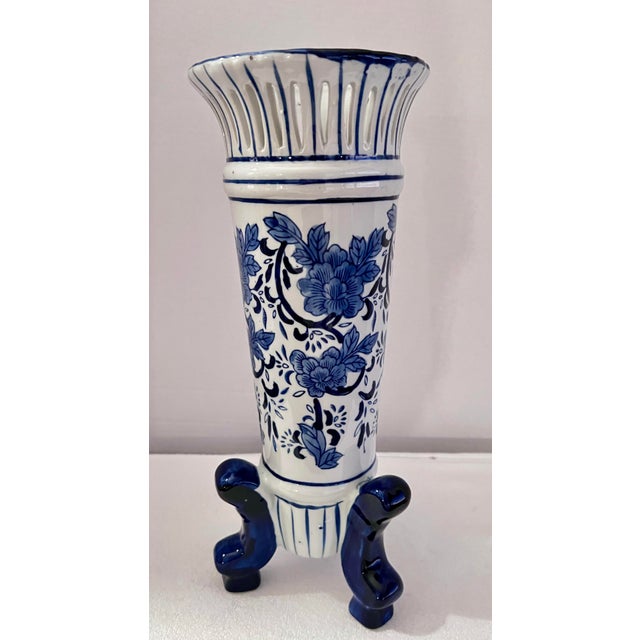 This footed Chinoiserie porcelain vase features a cobalt blue and white floral pattern with a cut-away reticulated rim....