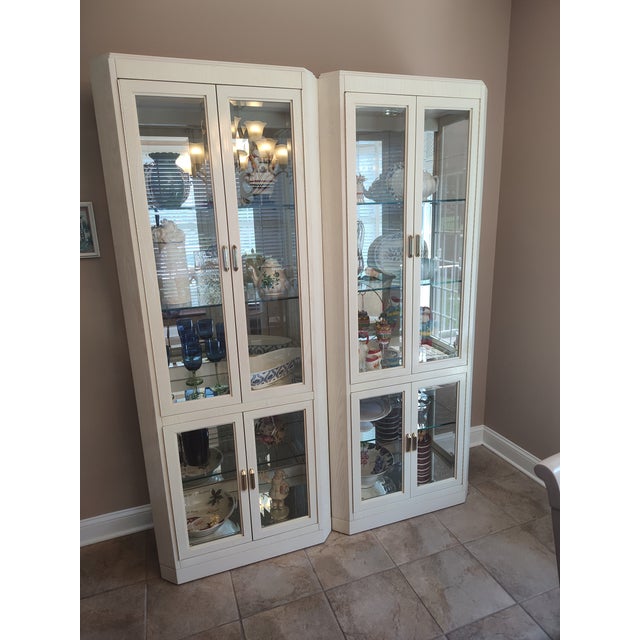 Monumental 1991 American of Martinsville Blonde Oak Lighted Curio Cabinets – Postmodern / Neoclassical Style Elevate your...