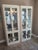 Monumental 1991 American of Martinsville Blonde Oak Lighted Curio Cabinets – Postmodern / Neoclassical Style Elevate your...
