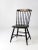 An antique Windsor chair featuring a classic birdcage spindle back and original black-painted finish accented with gold...