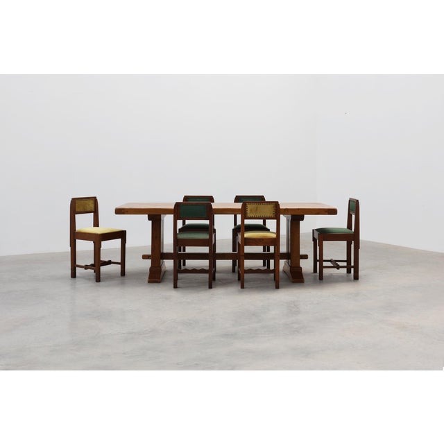 A robust French dining table crafted in solid oak, featuring a rectangular plank top supported by trestle legs joined by a...