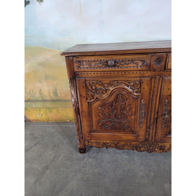 A very fine walnut sideboard, richly carved with vegetal motifs and foliate scrolls. the front features two doors with...