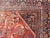This Antique Rug features a large central diamond design, replete with floral and sub-geometric motifs rendered in...