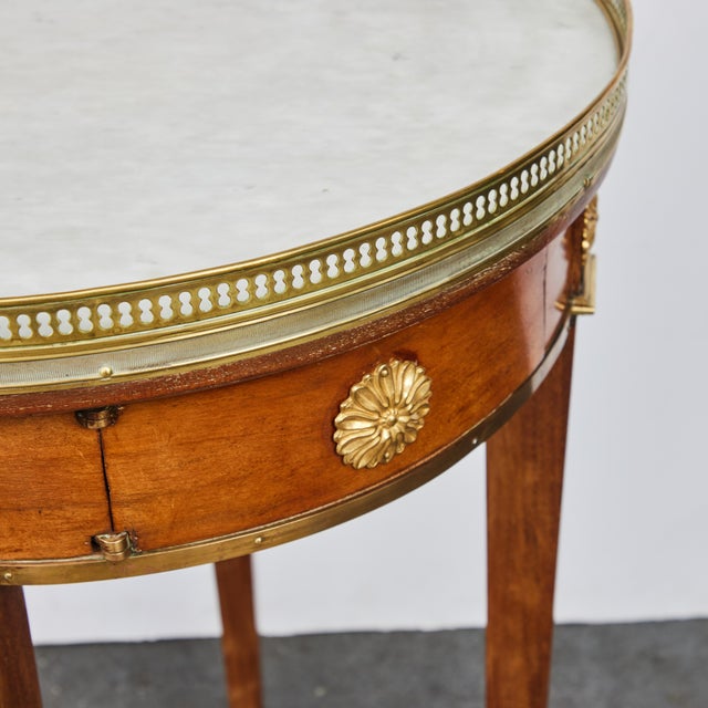 An unique, Louis XVI style, walnut, marble top gueridon with gilded bronze gallery, sabots and later medallions. Twisting...