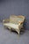 Woven wicker loveseat featuring a warm honey-toned frame, curved arms, and a shaped back with decorative lattice details....