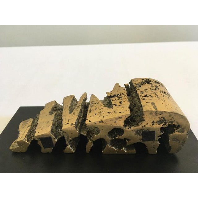 This engaging bronze sculpture on black wooden base, well represents a cheese shape, but the artist jokes with the shape...