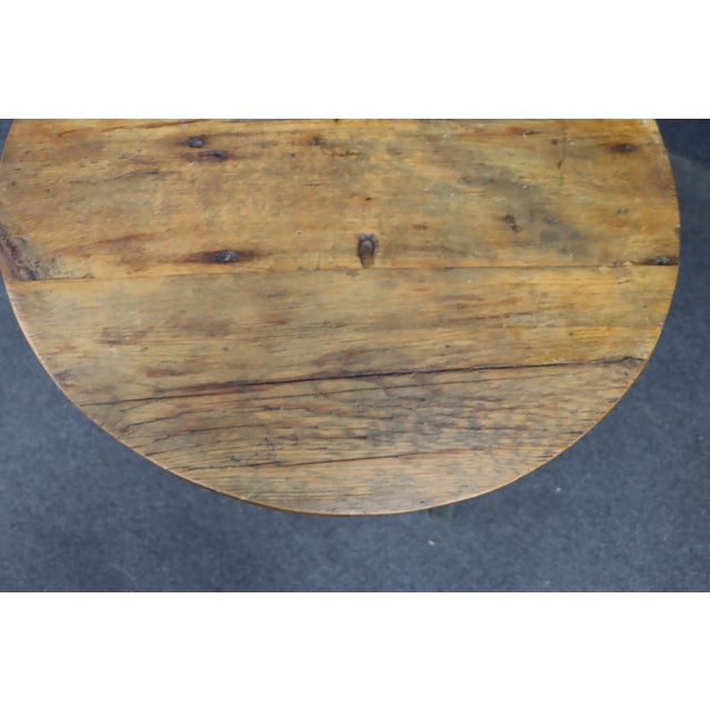 French country coffee table featuring a round pine top with visible grain, knots, and a warm honey-toned finish. The table...