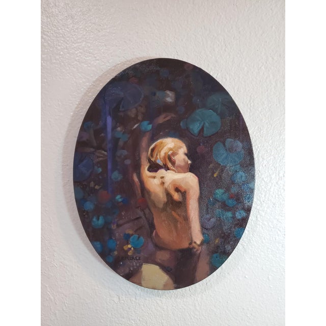This oil on canvas artwork features a figure in a serene pose, surrounded by a lush backdrop of lilies and aquatic...