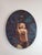 This oil on canvas artwork features a figure in a serene pose, surrounded by a lush backdrop of lilies and aquatic...