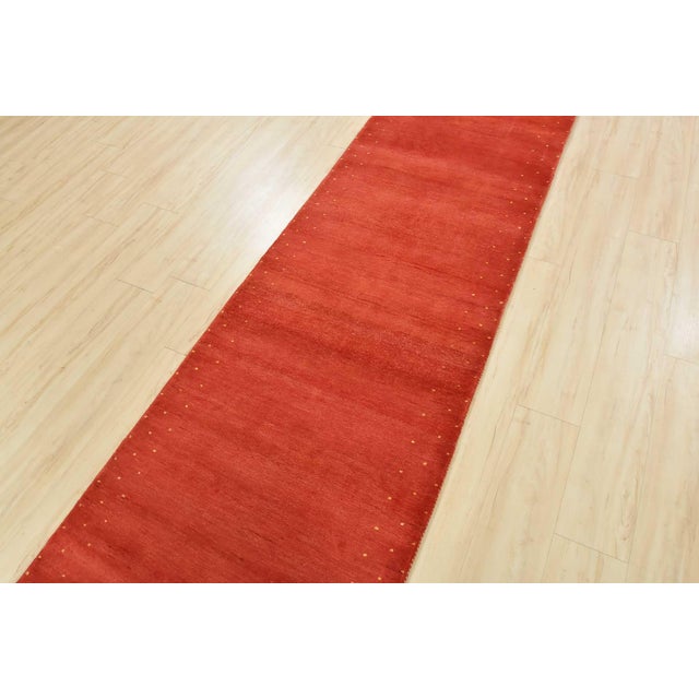 A contemporary Gabbeh runner hand-knotted with an all-wool pile on a cotton foundation. This oriental rug features a solid...