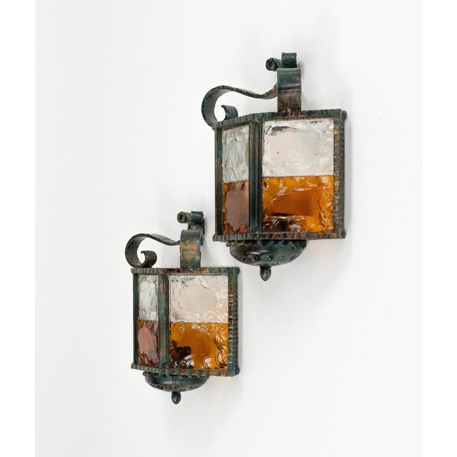 Midcentury amazing pair of sconces in wrought iron and multicolor hammered glass produced by Longobard the concurrent of...
