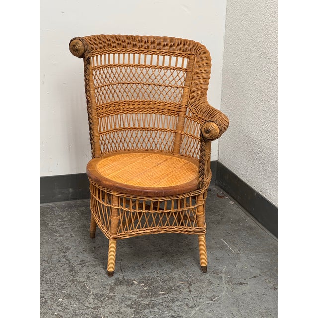 Design Plus Gallery presents a Vintage Woven Rattan Armchair. It has a rounded barrel-style back and integrated rolled...
