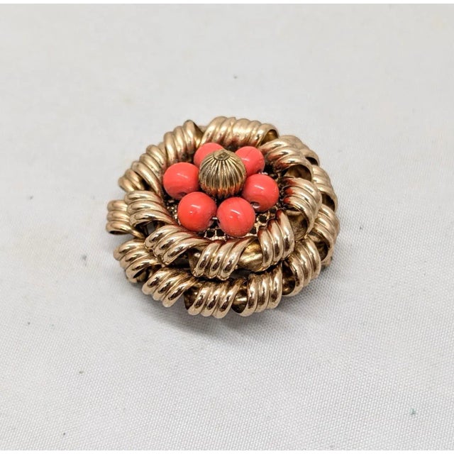 1950s round goldtone two layered circles of curled goldtone with beads of faux-coral and ribbed goldtone bead center...