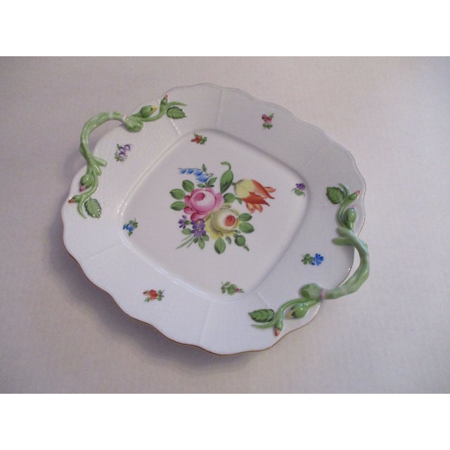 A Herend-Hungary hand painted porcelain serving plate. It has vine like green handles with rose buds. The plate is...