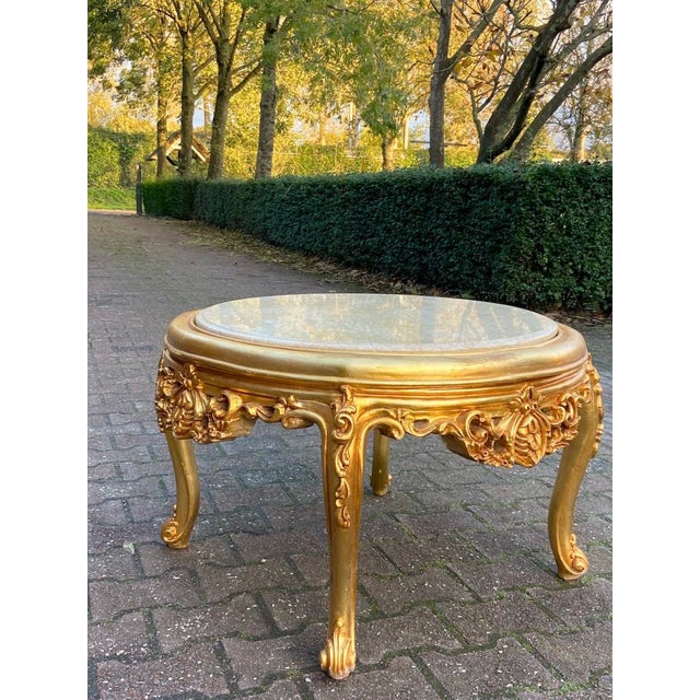 A refined 1960s French Louis XVI-style coffee table, crafted from solid beechwood with a luminous gilded finish and a...