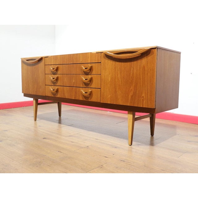 This Mid Century Modern Vintage British Teak Sideboard Credenza in the manor of Beautility embodies a beautiful classic...
