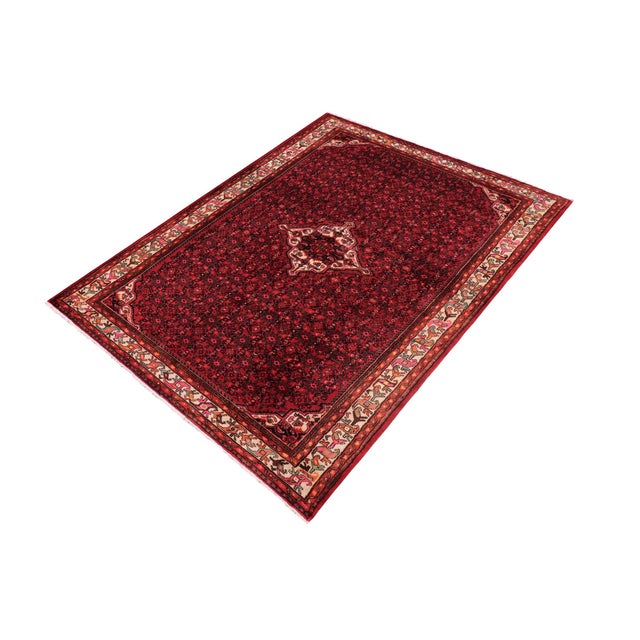 A beautiful hand-knotted wool rug measuring approximately 6'8" x 9'8". This striking carpet features a rich red field...
