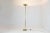 A sleek and sculptural French floor lamp, crafted entirely in solid brass with a minimalist silhouette that pays tribute...