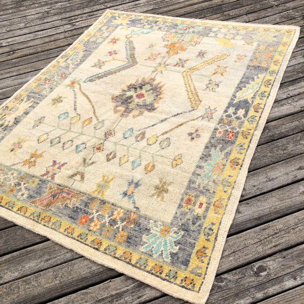 A contemporary take on the classic Oushak, this hand-knotted Turkish rug features a soft ivory field accented by subtle...