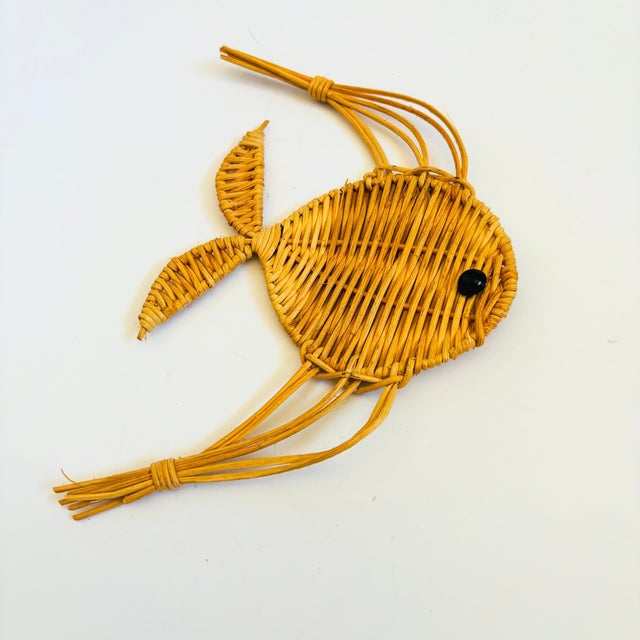 A vintage wicker wall hanging in the shape of a fish. Measures 6"W x 8"H x .25"D