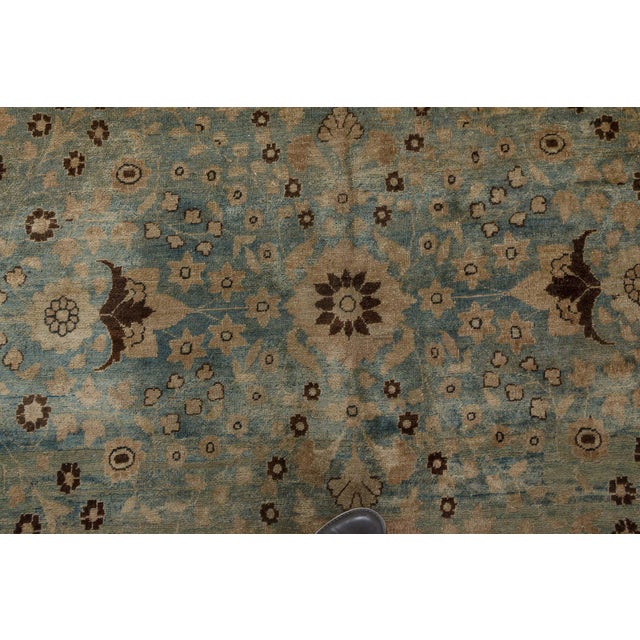 A late 19th century Persian Tabriz rug, the abrashed green field with an allover lattice of flowering vinery and palmettes...