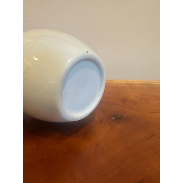 A graceful porcelain vase decorated with colorful birds perched among blooming branches. The soft white ground allows the...