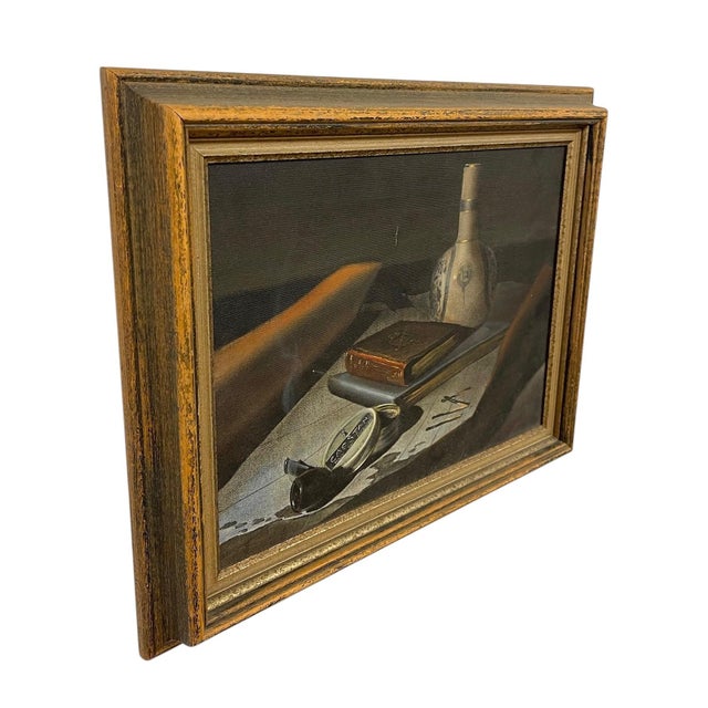 This vintage still presents a detailed tabletop composition featuring a bottle with decorative motifs, a closed book, a...