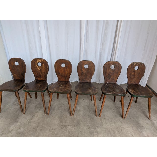 Vintage wooden dining chairs made in Yugoslavia, circa 1960s–1970s. The chairs feature a charming rustic folk design with...