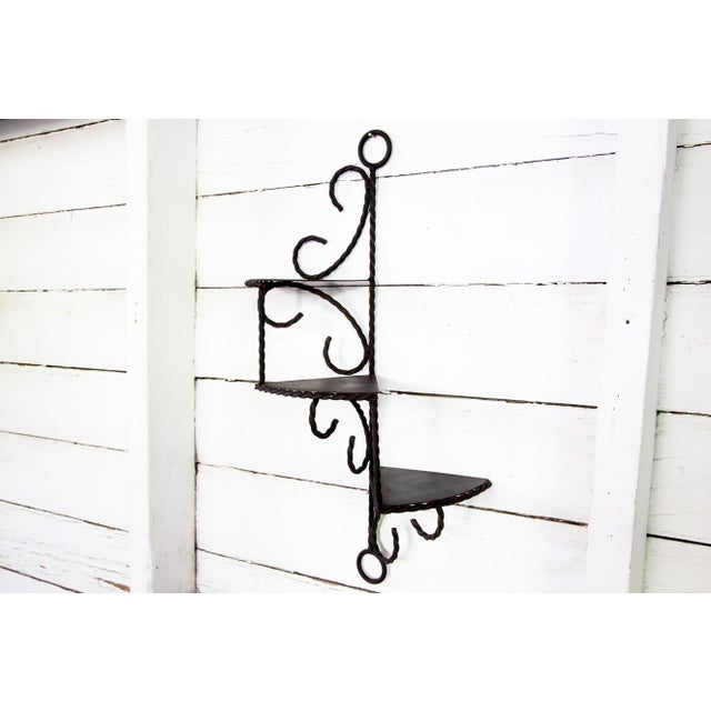 The wall brackets are a twisted rope design supporting pie-slice shaped metal shelves in patinated metal with a wrought-...