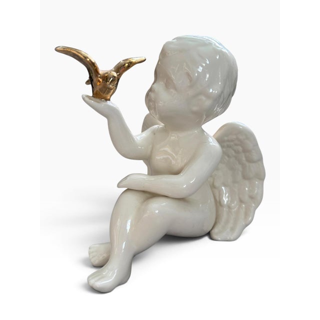 Elegant vintage figural cherub sculpture featuring a seated angel rendered in glossy white porcelain with beautifully...