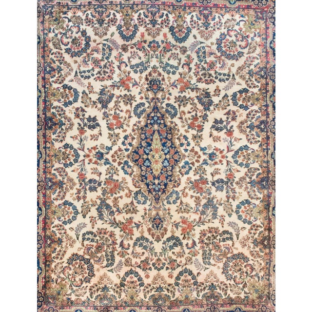 A beautiful early 20th century Persian Kirman rug with a large central floral medallion living in a field of even more...