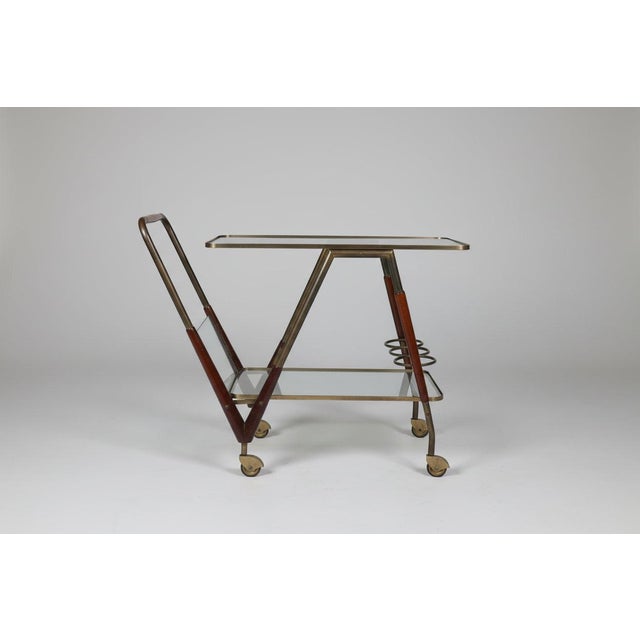 Iconic and now quite rare bar cart made in Italy featuring a brass frame and thick glass shelves.The mahogany detailing on...