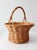 This vintage wicker basket features a rounded woven body, gently flared rim, and tall arched handle in a warm honey-toned...