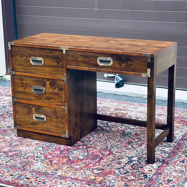 Vintage 1970s campaign style desk made in the USA by Bernhardt featuring four wooden dovetailed drawers with brass...