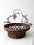 This large vintage basket features a handwoven base paired with a sculptural metal grapevine handle accented with leaf...