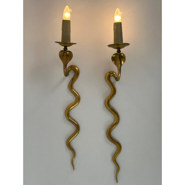 Set of two rare, elegant and highly decorative mid-century modern cast brass cobra sconces or wall lamps. Designed and...