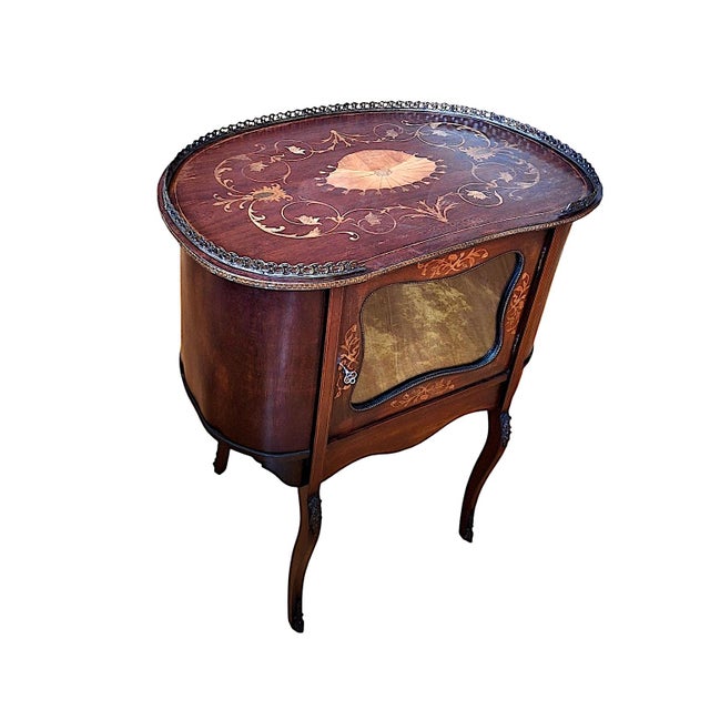 This embellished piece with a glass-front door is a vintage French Louis XV style kidney-shaped vitrine-table or a...