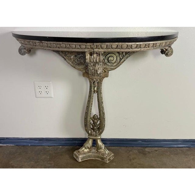 A striking Italian wall-mounted console table, richly carved and silver-gilt with classical motifs and a bold, sculptural...