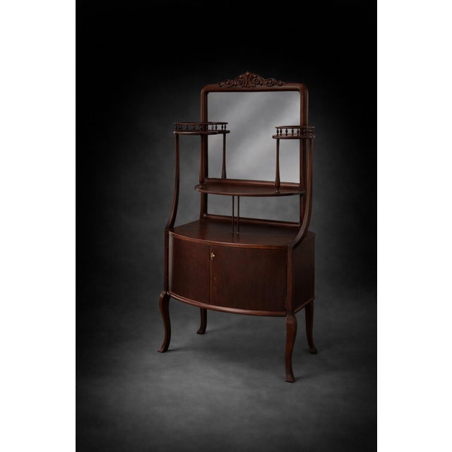 A charming vintage mahogany vanity washstand featuring an elegant mirror, decorative carved crest, and tiered display...