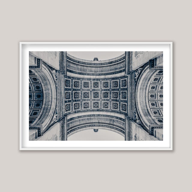 A blue and sepia-toned black-and-white study of the Arc de Triomphe in Paris, France. Photographed from directly beneath...