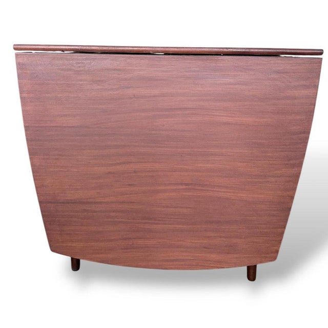 A beautifully designed mid-century drop leaf dining table by Elliots of Newbury (EON), crafted in richly toned teak and...