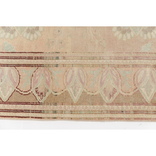 This is a vintage Turkish Oushak rug from the Mid 20th Century. The piece was hand-knotted.