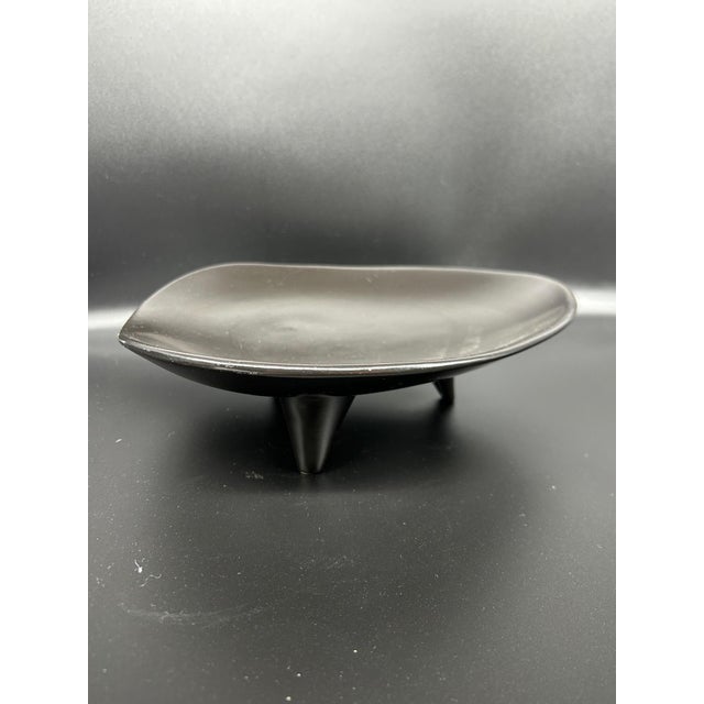 A black glazed ceramic trinket tray resting on three triangular feet, 1950s