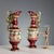 Pair of polychrome ceramic jugs. The body features a band with classical-style decal scenes. The handle is shaped like a...