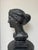 A substantial Neoclassical female bust cast in solid concrete and finished in black. The sculpture depicts an idealized...