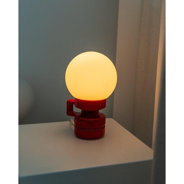This beautiful table lamp in mid-century vintage style with a red ceramic base in steps and a white glass shade provides...
